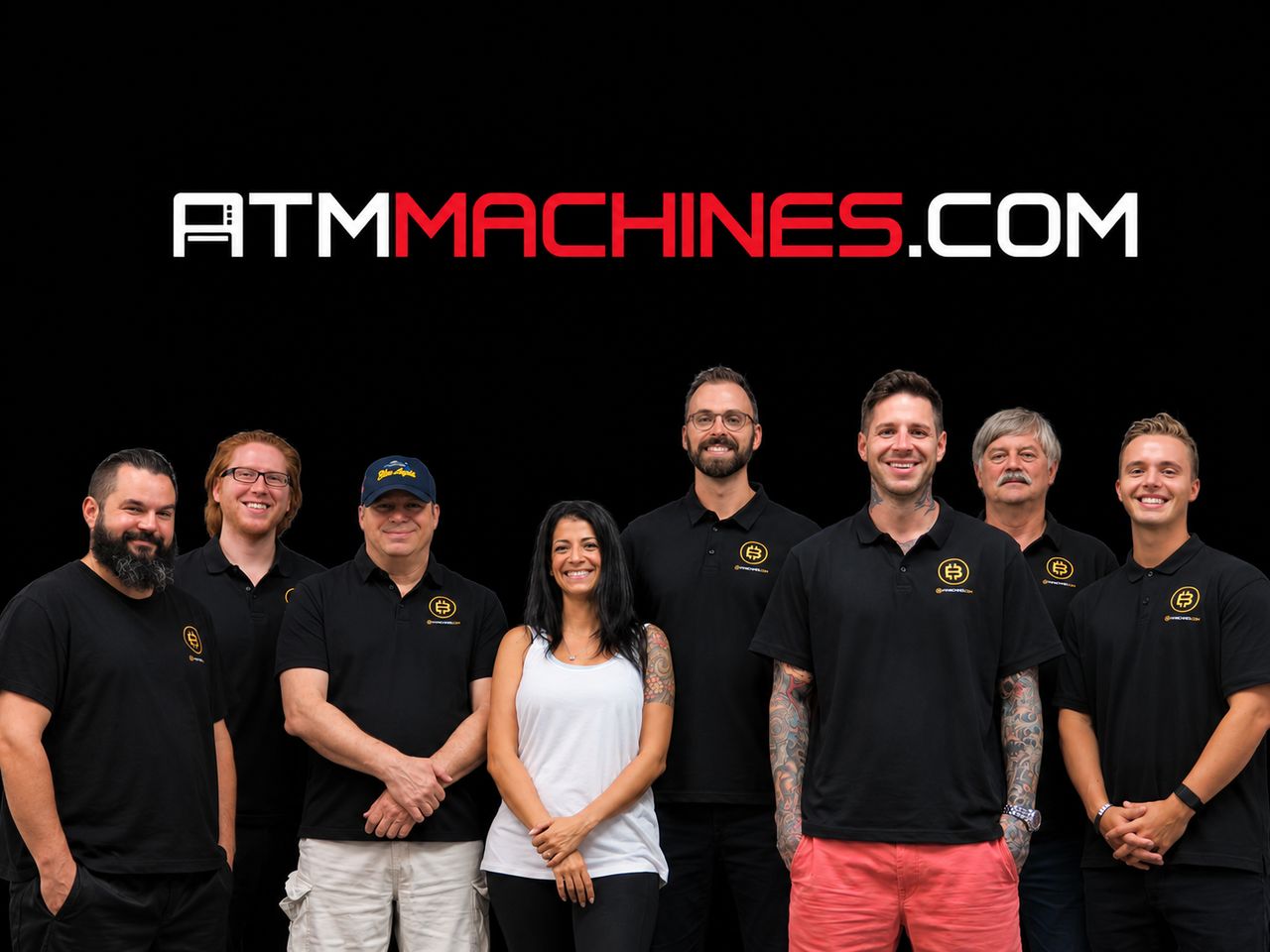 Justin Gilmore standing with the eight-person ATMmachines.com team in front of the ATMmachines.com logo.